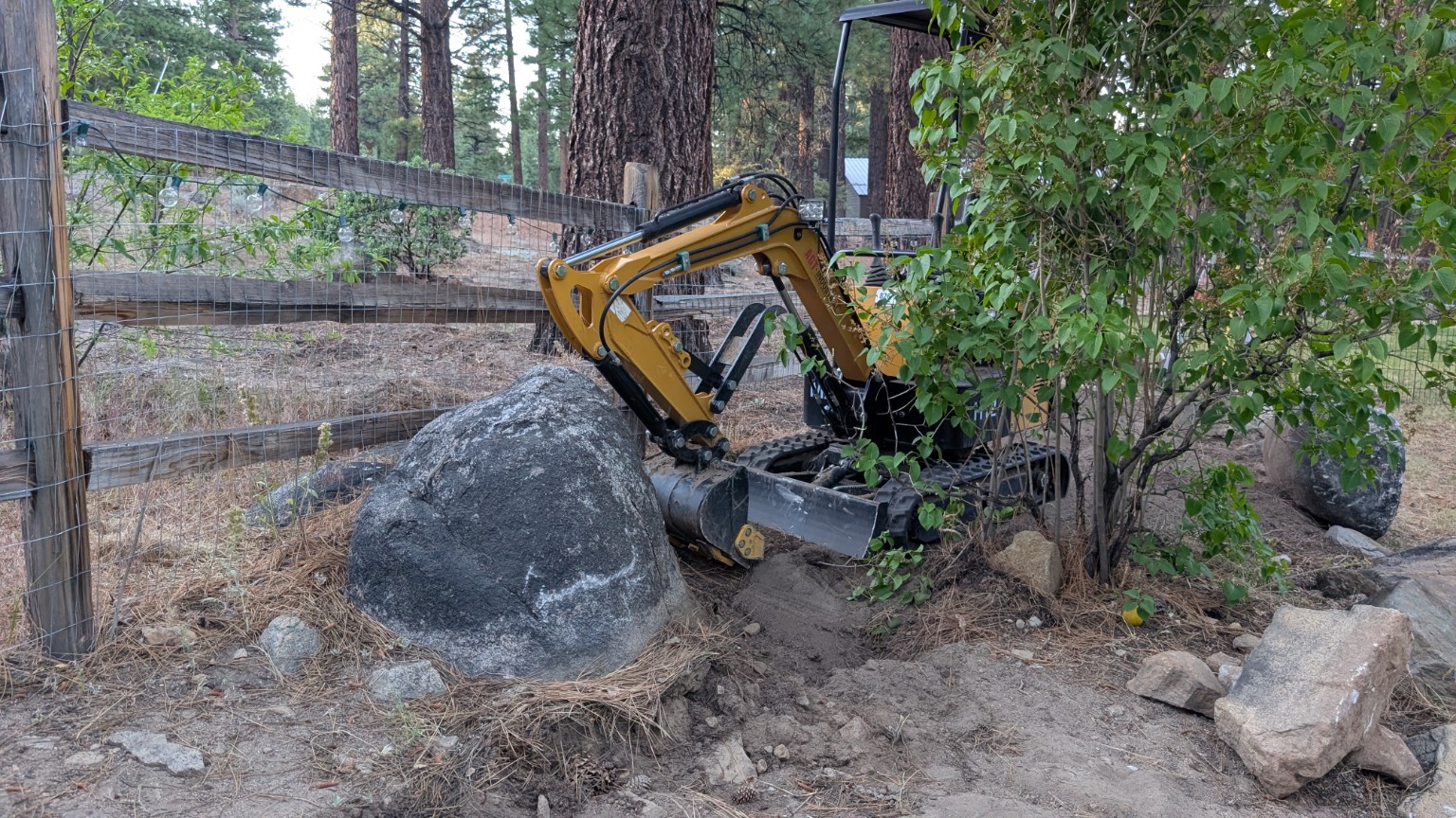 A large granite boulder beside a compact excavator in the Sierra Nevada
