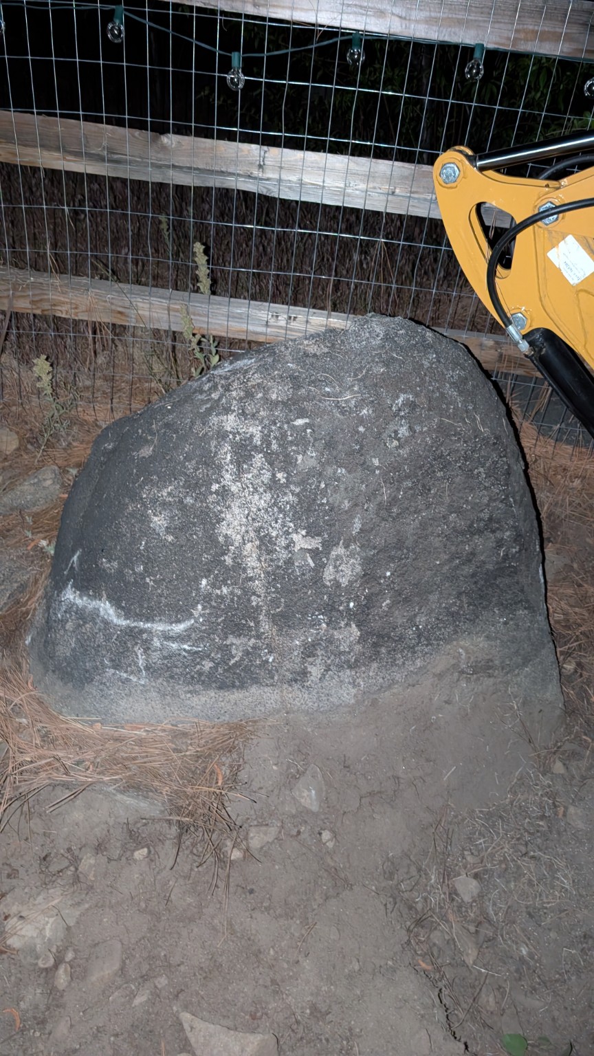 Large granite boulder beside a compact excavator